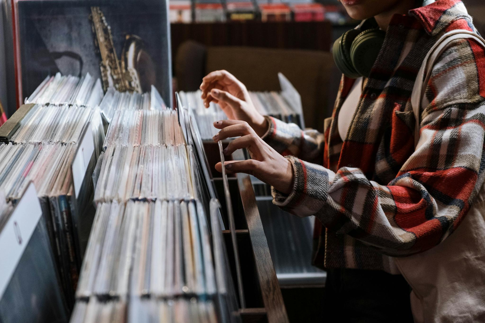 A person browses through a selection of vinyl records in a vintage music shop.