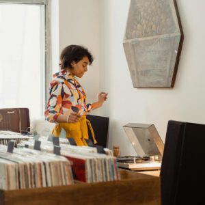 A woman enjoys browsing vinyl records and listening to music indoors in a stylish store.