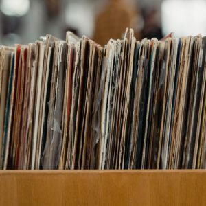 Stack of vintage vinyl records stored in a wooden crate, showcasing a retro vibe.