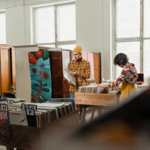 Two people browse vinyl records in a cozy, vintage-themed record shop.